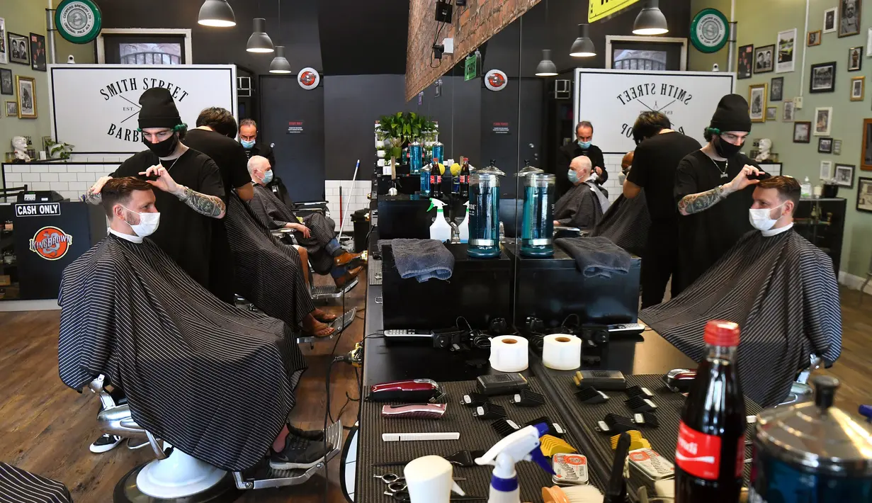 Para pria memotong rambut di barber shop di Melbourne, Australia, Senin (19/10/2020). Warga Kota Melbourne, pada Senin (19/10), akhirnya bisa bernafas lega saat sejumlah pembatasan dilonggarkan setelah menjalani lockdown tahap keempat yang ketat selama sekitar 100 hari. (William WEST/AFP)