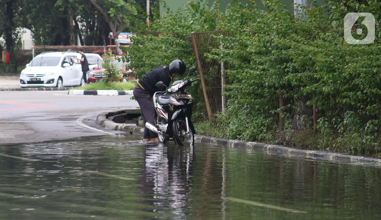 Pengendara memanfaatkan genangan air untuk mencuci kendaraan di Jalan HBR Motik Kemayoran, Jakarta, Selasa (25/2/2020). Hujan yang mengguyur Jakarta sejak Senin (24/2) malam membuat sejumlah kali meluap dan menyebabkan banjir. (Liputan6.com/Helmi Fithriansyah)