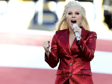 Penyanyi Lady Gaga menyanyikan lagu kebangsaan AS saat pembukaan Super Bowl 50 di Santa Clara, California, Minggu (7/2). Mengenakan busana dari Gucci, Mother Monster itu tampil serba merah seperti bendera negaranya. (Streeter Lecka/Getty Images/AFP)