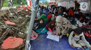 Murid-murid korban gempa belajar pada tenda darurat yang dibangun di halaman sekolah di SDN Gintung, Mangunkerta, Cianjur, Jumat (23/12/2022). Lebih dari sebulan sejak musibah gempa bumi 5,2 SR sejumlah murid sekolah di Cianjur masih belajar pada tenda darurat. (merdeka.com/Arie Basuki)