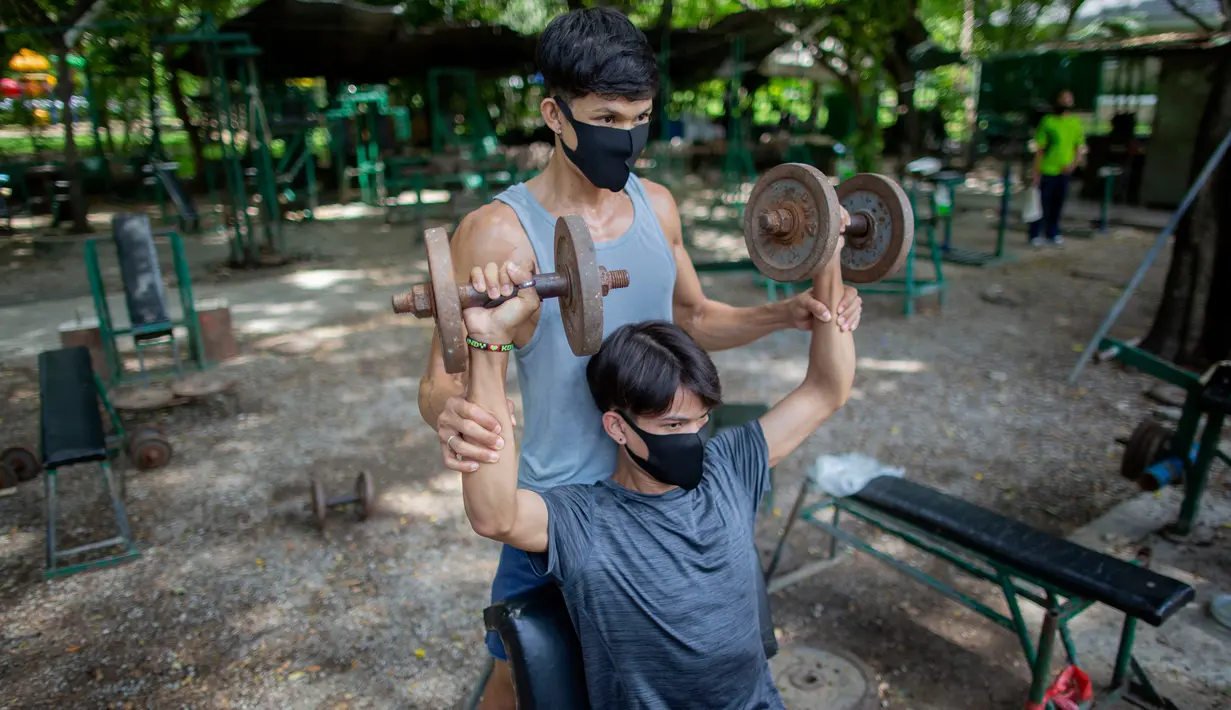 Dua pria berolahraga di gym luar ruangan di sebuah taman di Bangkok, Thailand, Rabu (10/6/2020). Kehidupan sehari-hari di ibukota kembali normal karena pemerintah Thailand terus melonggarkan pembatasan terkait dengan menjalankan bisnis di ibukota Bangkok. (AP Photo/Gemunu Amarasinghe)