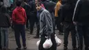 <p>Seorang pria berjalan dengan tas berisi roti yang baru saja dibeli ketika warga Palestina berkerumun di luar toko roti untuk membeli roti di Rafah di Jalur Gaza selatan pada 15 Februari 2024. (MOHAMMED ABED/AFP)</p>