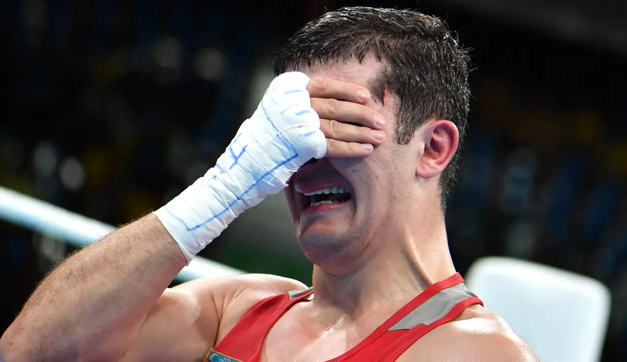 Atlet tinju Uzbekistan, Rustam Tulaganov menangis sambil menutupi wajahnya dengan tangan usai menang atas petinju Azerbaijan, Abdulkadir Abdullayev dalam pertandingan tinju putra kelas 91 kg di Olimpiade Rio 2016, 10 Agustus 2016. (AFP PHOTO/Yuri CORTEZ)