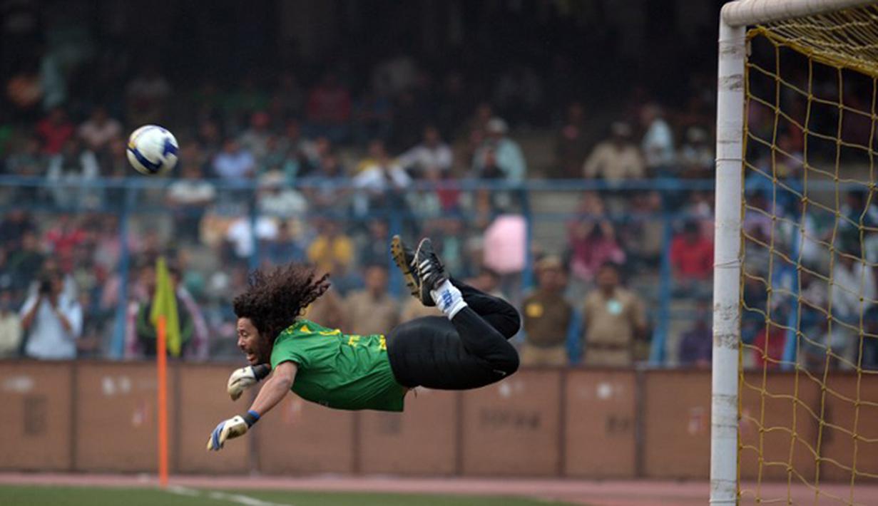 Kiper asal Kolombia ini meski masih dalam upaya menyelamatkan gawang, tapi aksi Rene Higuita benar-benar gila. Apalagi, kalau bukan tendangan kalajengking untuk menghalau bola yang akan masuk ke gawangnya sendiri. (AFP PHOTO/Dibyangshu SARKAR)