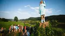 Orang-orang berkumpul dekat patung kayu yang menampilkan sosok Melania Trump di pinggiran Sevnica, Slovenia, 5 Juli 2019. Patung raksasa seukuran manusia itu  menampilkan sosok Melania yang mengenakan gaun biru yang dikenakan pada pelantikan suaminya tahun 2017. (Jure Makovec/AFP)