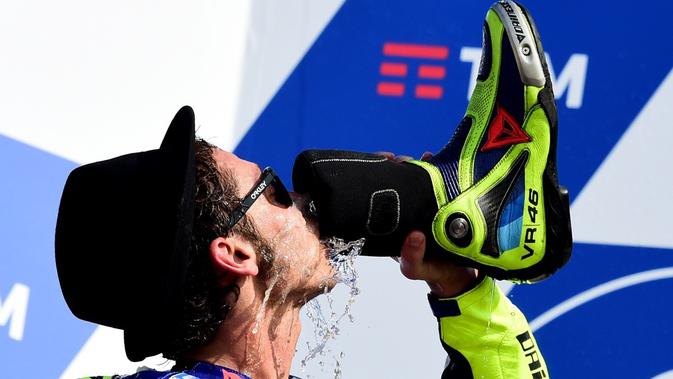 Valentino Rossi merayakan kemenangan dengan minum sampanye dari sepatunya saat berada di podium MotoGP San Marino 2016 di Sirkuit Misano. (AFP/Giuseppe Cacace)