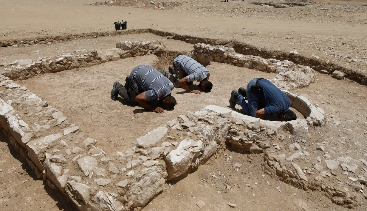 Pekerja muslim dari otoritas barang antik Israel berdoa di reruntuhan salah satu masjid kuno yang baru ditemukan di kota Rahat, gurun Negev pada 18 Juli 2019. Masjid tertua yang pernah ditemukan di Israel itu diperkirakan dibangun sekitar 1.200 tahun silam. (MENAHEM KAHANA/AFP)