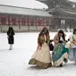 Pengunjung yang mengenakan pekaian tradisional "Hanbok" di salju berjalan melalui Istana Gyeongbok, istana kerajaan utama selama Dinasti Joseon dan salah satu landmark terkenal Korea Selatan di Seoul, Korea Selatan, 15 Desember 2022. (AP Photo/Ahn Young-joon)