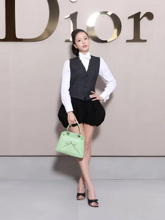 Princess Dior satu ini tampil chic dengan kemeja putih berdasi pita yang dilapisi dengan vest hitam. Skort hitam, heels berpita, dan siluet tas terbaru Dior hijau pastel jadi aksesori pelengkap [Dior]