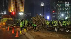Petugas Dinas Kehutanan DKI Jakarta membongkar instalasi bambu Getah Getih di Bundaran Hotel Indonesia (HI), Kamis (18/7/2019) dini hari. Karya seni tersebut rencananya akan diganti dengan taman dan setelah dibongkar, bambu itu akan dibawa ke tempat pembuangan sampah. (Liputan6.com/Herman Zakharia)