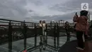 Warga berfoto saat mengisi libur Tahun Baru dengan menikmati pemandangan Kota Jakarta dari Skywalk Senayan Park, Sabtu (1/1/2022). Warga ramai-ramai datang untuk berburu foto pada spot-spot yang instagramable di Skywalk Senayan Park. (Liputan6.com/Johan Tallo)