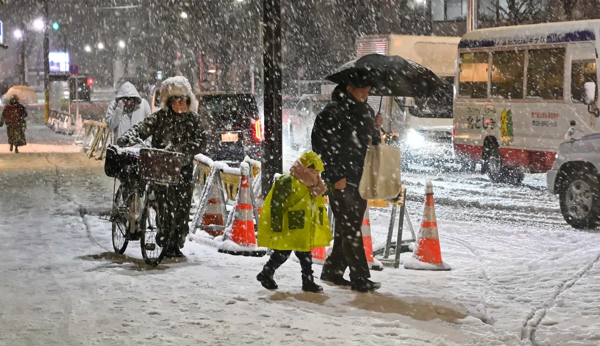 Orang-orang berjalan di trotoar yang tertutup salju di Distrik Nerima, Tokyo pada tanggal 5 Februari 2024. Hujan salju lebat melanda wilayah Tokyo dan sekitarnya. (Kazuhiro NOGI/AFP)