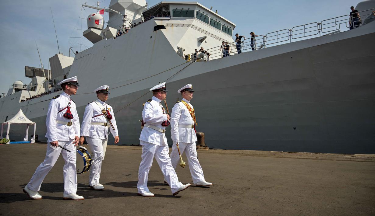 Para anggota Orkestra Marinir Belanda berjalan di samping kapal perang HNLMS De Ruyter di pelabuhan Tanjung Perak, Surabaya, Jawa Timur pada Kamis 14 Mei 2026. (JUNI KRISWANTO/AFP)