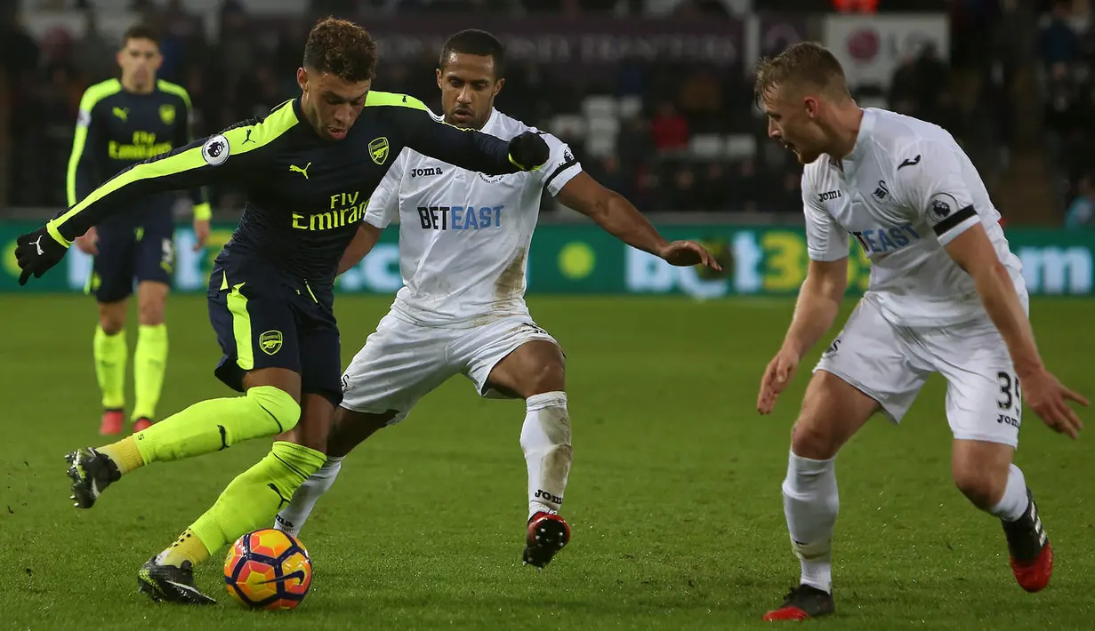 Gelandang Arsenal, Alex Oxlade-Chamberlain, berusaha melewati hadangan pemain Swansea. Meski bermain tandang, The Gunners sudah tampil menyerang sejak babak pertama baru dimulai. (AFP/Geoff Caddick)