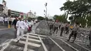Massa aksi 31 Maret melintasi petugas polisi yang sedang memasang kawat berduri di sekitar Istana Negara, Jakarta, Jumat (31/3). Kawat berduri tersebut dipasang untuk mengantisipasi ricuh aksi 31 Maret. (Liputan6.com/Immanuel Antonius)