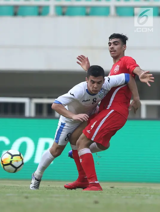 Gelandang Uzbekistan, Kenjabaev Islom (kiri) berebut bola dengan pemain Bahrain pada laga PSSI Anniversary Cup 2018 di Stadion Pakansari, Kab Bogor, Senin (30/4). Laga kedua tim berakhir imbang 3-3. (Liputan6.com/Helmi Fithriansyah)