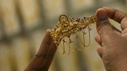 Seorang pelanggan memegang perhiasan emas selama festival Hindu 'Akshaya Tritiya', hari keberuntungan dalam kalender Hindu untuk membeli barang-barang berharga, di ruang pamer perhiasan di Chennai, India, Selasa (3/5/2022). Membeli emas adalah kegiatan yang populer di Akshaya Tritiya, karena ini adalah simbol utama kekayaan dan kemakmuran. (Arun SANKAR / AFP)