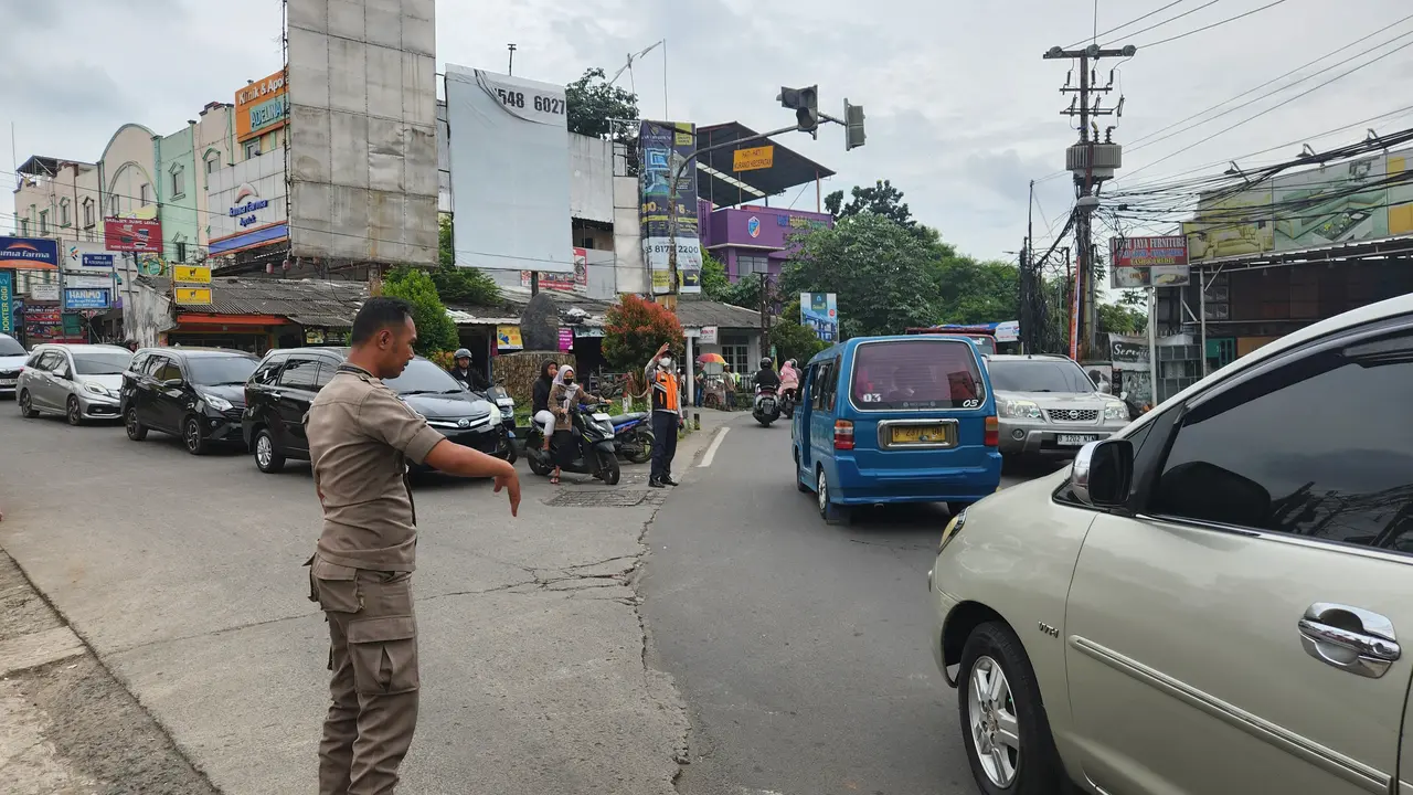 Anggota Satpol PP Kota Depok berjaga dan mengatur lalu lintas di simpang tugu batu Sawangan, Depok.