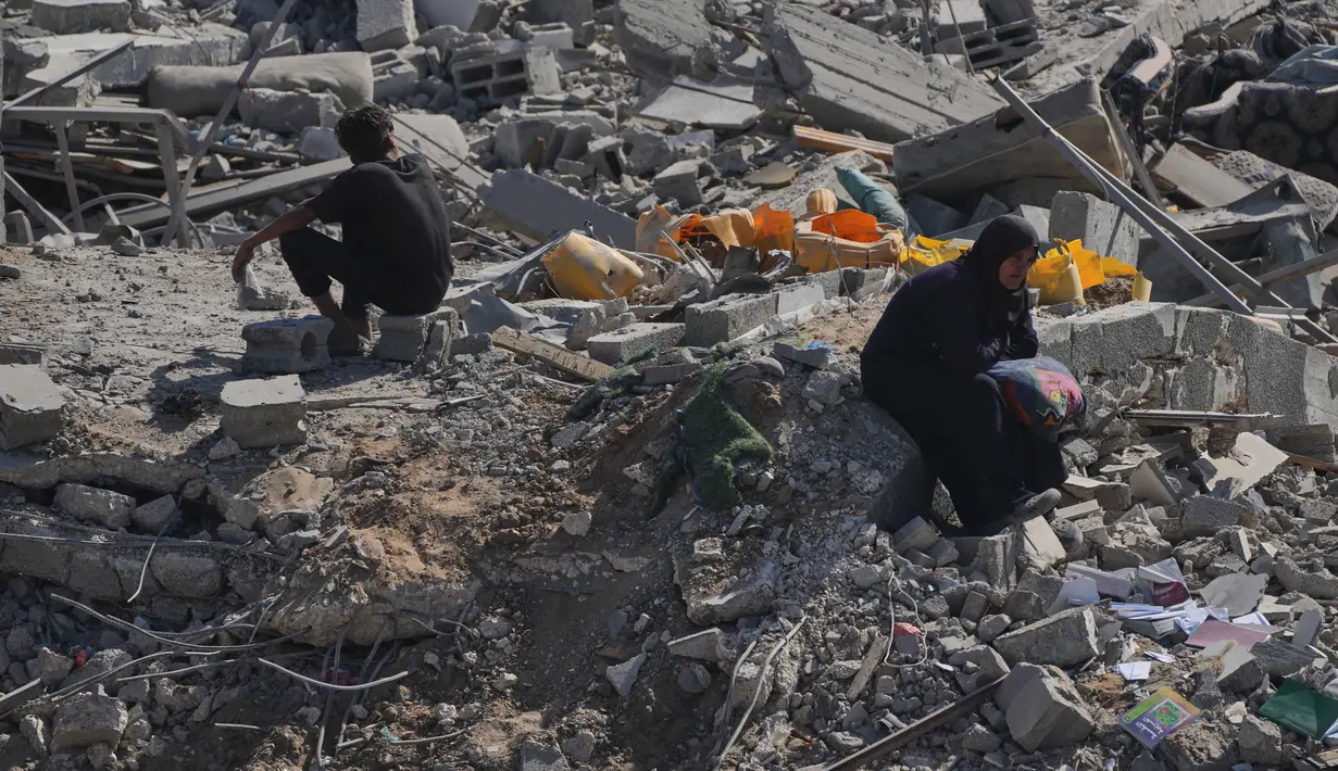 Seorang wanita Palestina yang terpaksa mengungsi duduk di atas puing-puing bangunan yang hancur di kawasan Sheikh Radwan yang parah kerusakannya di Kota Gaza, Sabtu 11 Oktober 2025. (AP Photo/Abdel Kareem Hana)