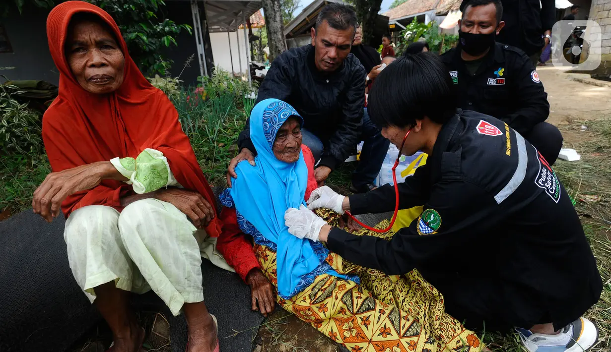Tenaga medis dari Dinas Kesehatan Kabupaten Karawang melakukan pemeriksaan kesehatan seorang lansia pengungsi korban gempa bumi di desa Mangunkerta, kecamatan Cugenang, Cianjur, Jawa Barat, Rabu (23/11/2022). Hari ketiga pasca gempa magnitudo 5,6 mengguncang Cianjur, Kementerian Kesehatan (Kemenkes) mengirimkan sejumlah dokter termasuk dokter spesialis dan kebutuhan obat-obatan. (merdeka.com/Arie Basuki)