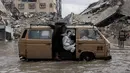 Sebagaimana diketahui, sebagian besar Kota Gaza hancur menjadi puing-puing dihantam serangan udara Israel sejak 7 Oktober 2023. Tampak dalam foto, orang-orang menaiki kendaraan yang dikendarai menerobos banjir di kamp darurat yang menampung warga Palestina yang terlantar setelah hujan deras di Kota Gaza pada Selasa 25 November 2025. (Omar AL-QATTAA/AFP)
