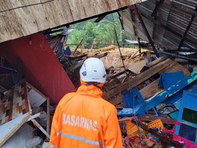 Foto selebaran yang diambil dan dirilis pada 7 Maret 2023 oleh kantor Kementerian Komunikasi dan Informatika Natuna ini menunjukkan tim penyelamat sedang memeriksa kerusakan akibat tanah longsor di Natuna, Kepulauan Riau (Kepri).  Kapolres Natuna Ajun Komisaris Besar Nanang Budi Santosa mengatakan, saat ini masih ada sekitar 47 orang dinyatakan hilang dan 27 rumah tertimbun material tanah longsor. (HO / Natuna ministry of communication / AFP)