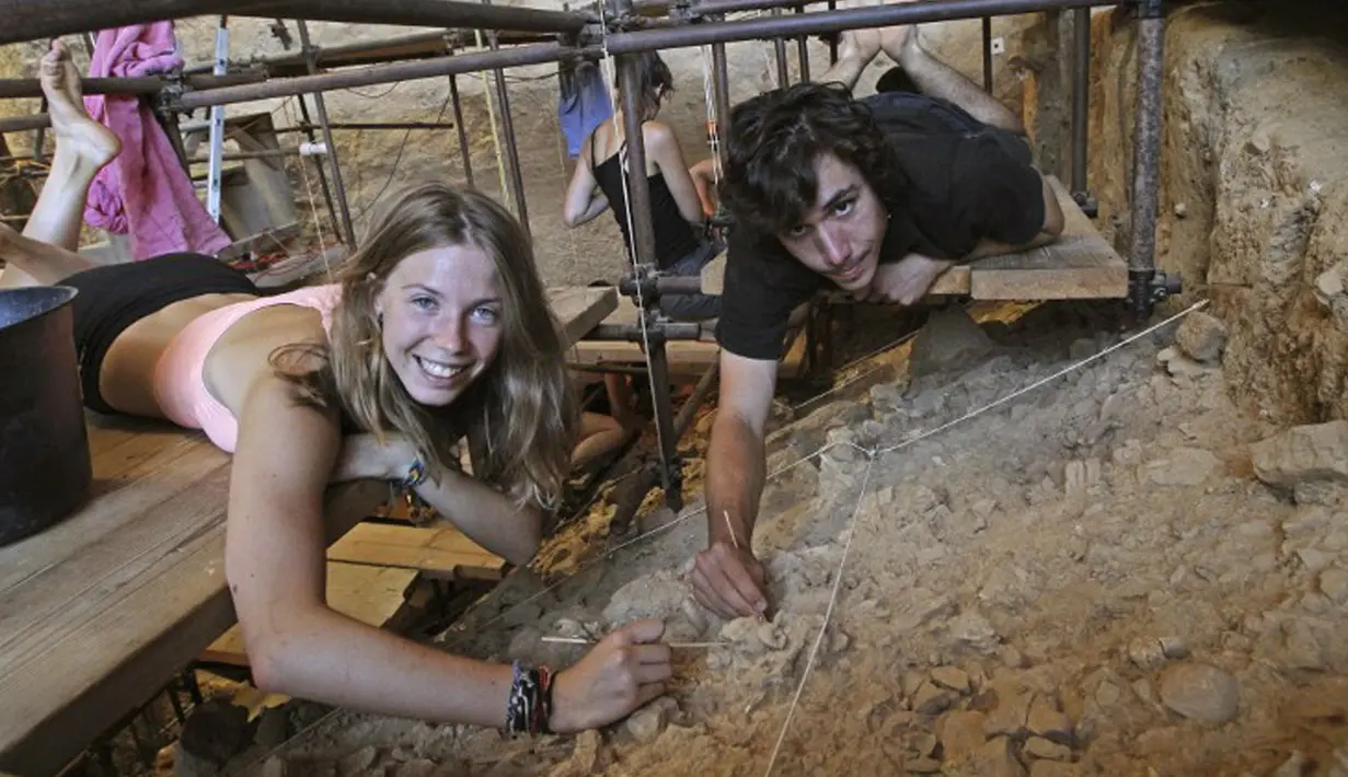 Sukarelawan arkeologi, Camille dan Valentin (kanan) berpose di Gua Arago, Tautavel, Prancis (28/7/2015). Camille (16) menemukan sebuah gigi manusia dewasa berusia 560.000 tahun. (AFP PHOTO/RAYMOND ROIG)