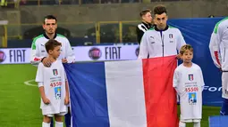 Pemain Italia, Stephan El Shaarawy (kanan) dan Alessandro Florenzi memegang bendera Prancis pada laga persahabatan melawan Rumania di Stadion Renato Dall'Ara, Bologna, Rabu (18/11/2015) dini hari WIB.  (AFP Photo/Giuseppe Cacace)