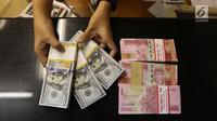 Pekerja menunjukan mata uang Rupiah dan Dolar AS di Jakarta, Rabu (19/6/2019). Nilai tukar rupiah terhadap dolar Amerika Serikat (AS) sore ini Rabu (19/6) ditutup menguat sebesar Rp 14.269 per dolar AS atau menguat 56,0 poin (0,39 persen) dari penutupan sebelumnya. (Liputan6.com/Angga Yuniar )