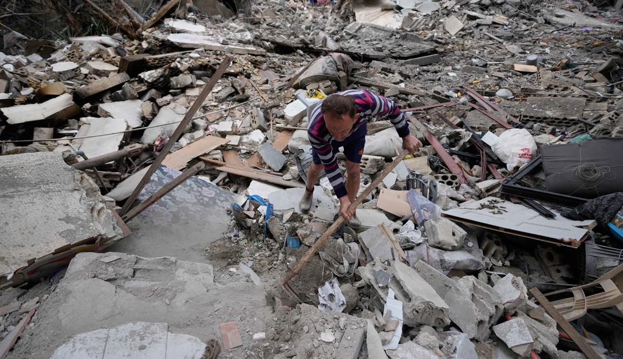 Sementara itu, Kementerian Kesehatan Lebanon melaporkan jumlah korban tewas akibat serangan Israel telah melampaui 1.072 orang. Tampak dalam foto, seorang pria menyingkirkan puing-puing sambil mencari barang-barang yang hilang dari rumahnya yang hancur akibat serangan udara Israel di kota pelabuhan Tyre, Lebanon selatan, Kamis, 26 Maret 2026. (AP Photo/Hussein Malla)
