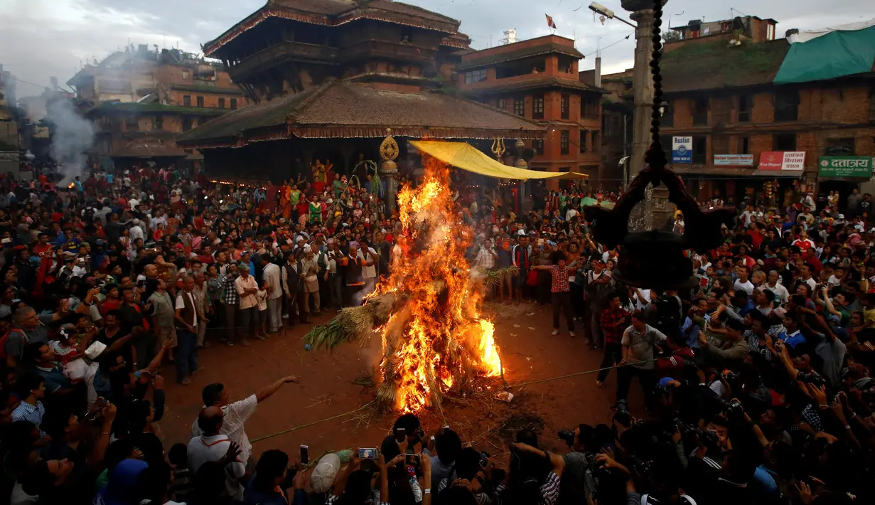 Sejumlah warga menyaksikan pembakaran boneka dari jerami yang dianggap sebagai setan Ghantakarna selama Festival Ghantakarna di kota kuno Bhaktapur, Nepal, Senin (1/8). (REUTERS/Navesh Chitrakar)