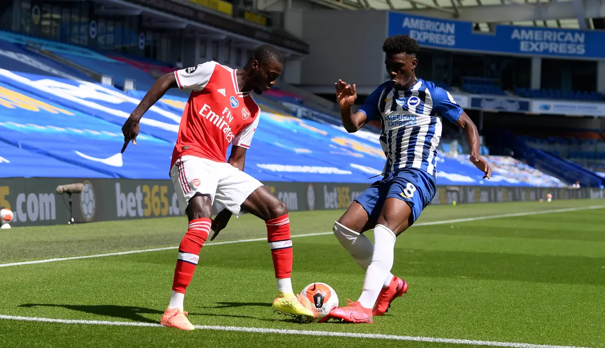 Winger Arsenal, Nicolas Pepe berebut bola dengan pemain Brighton & Hove Albion, Yves Bissouma pada lanjutan pertandingan Liga Inggris di The American Express Community Stadium, Sabtu (20/6/2020). Sempat unggul, Arsenal justru tumbang 1-2 di tangan Brighton. (Mike Hewitt/Pool via AP)