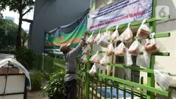 Pedagang mengambil sembako yang digantung di rak kayu sisi jalan di kawasan Rawa Barat, Jakarta Selatan, Kamis (14/5/2020). Selama masa pandemi COVID-19, pihak kelurahan dan masjid sekitar menyediakan paket berisi mi instan, telur, dan masker untuk warga yang membutuhan. (merdeka.com/Imam Buhori)