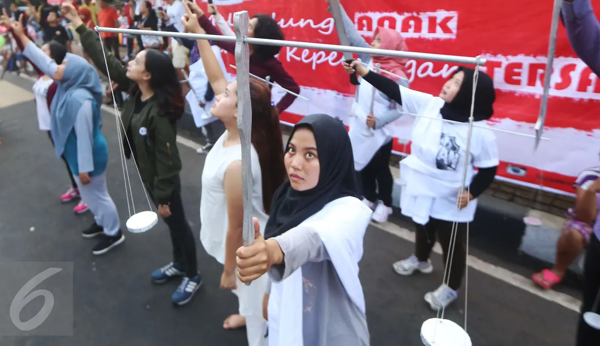 Relawan Kawan8 dan Mahasiswa IKJ membawa atribut timbangan yang melambangkan keadilan saat menggelar flashmob di Jalan Jenderal Sudirman, Jakarta, Minggu (5/3). (Liputan6.com/Helmi Afandi)
