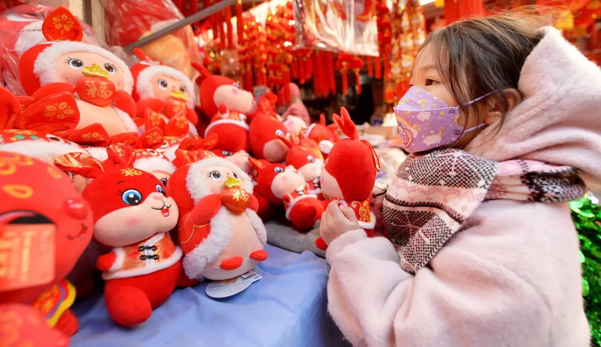 Seorang anak memilih mainan menjelang Hari Tahun Baru di sebuah pasar di Qingdao, di provinsi Shandong timur China pada 25 Desember 2022. Warga China mulai berburu pernak-pernik Tahun Baru seperti lampion, kartu tahun baru, baju, dan hiasan rumah. (AFP/STR)