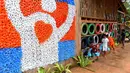 Anak-anak menyirami tanaman di Coconut School, Taman Nasional Kirirom Kamboja, 1 Oktober 2018. Pintu masuk sekolah ini dihiasi dengan mural bendera Kamboja yang terbuat dari tutup botol berwarna-warni. (TANG CHHIN Sothy/AFP)