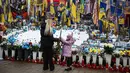 Ribuan tentara dari kedua pihak tewas di medan perang, sementara warga sipil Ukraina bertahun-tahun hidup di bawah ancaman serangan udara, pemadaman listrik, dan krisis air bersih. Tampak dalam foto, seorang wanita dan seorang anak mengunjungi tugu peringatan sementara untuk tentara Ukraina dan asing di Lapangan Kemerdekaan, Kyiv, saat peringatan keempat invasi Rusia ke Ukraina, Selasa 24 Februari 2026. (HENRY NICHOLLS/AFP)