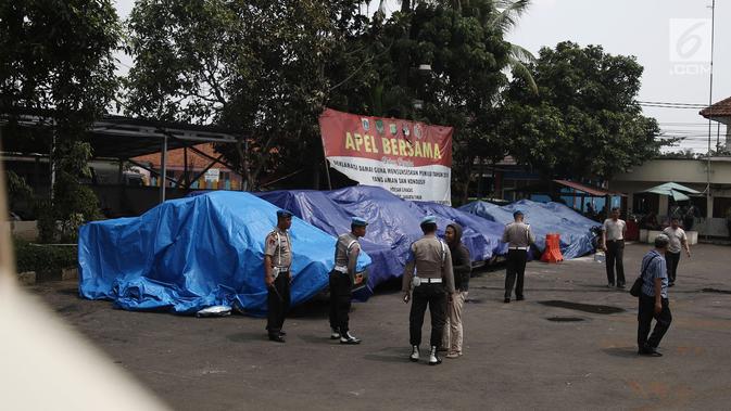Terpal menutupi sejumlah mobil yang dirusak di Polsek Ciracas, Jakarta, Rabu (12/12). Aksi massa tersebut diduga akibat tidak puas dengan penanganan kasus di Polsek Ciracas. (Liputan6.com/Herman Zakharia)