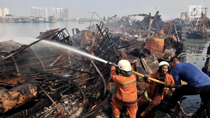 Petugas pemadam kebakaran melakukan pendinginan kapal yang ludes dilalap api di Pelabuhan Muara Baru, Jakarta, Minggu (24/2). Saat ini, polisi juga telah memeriksa tujuh saksi terkait kebakaran tersebut. (Merdeka.com/Iqbal Nugroho)