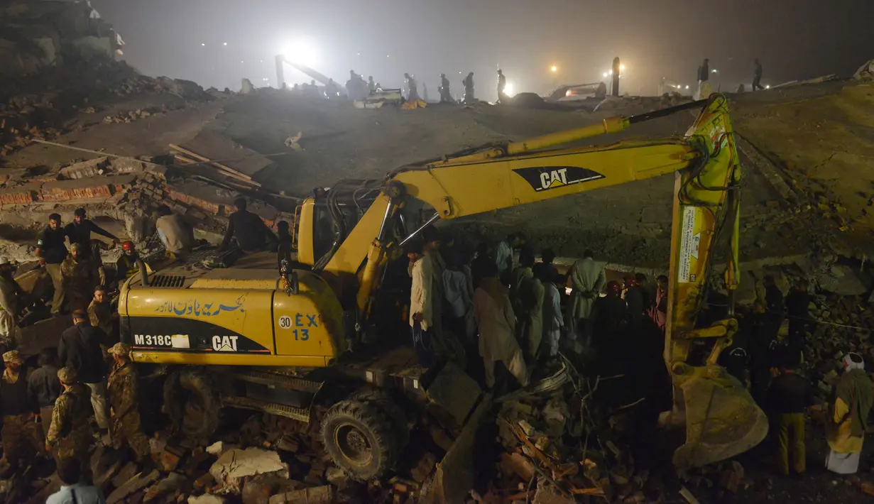 Petugas menggunakan alat berat untuk mencari korban di reruntuhan pabrik berlantai lima yang ambruk di Lahore, Pakistan Timur, Rabu (4/11)malam waktu setempat. Sedikitnya 16 orang tewas dan 40 luka-luka akibat kejadian tersebut. (AFP PHOTO/Arif Ali)