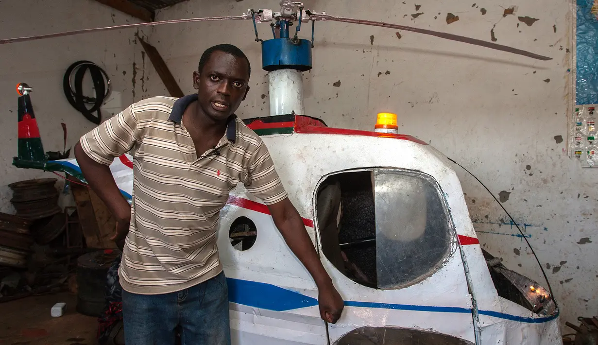 Felix Kambwiri berdiri di dekat helikopter buatannya di garasi rumahnya di Desa Gobede, Malawi, 19 Februari 2016. Helikopter yang dikerjakan sejak empat bulan lalu itu dibuat dari rongsokan besi tua dan fiberglass. (Amos Gumulira/AFP)