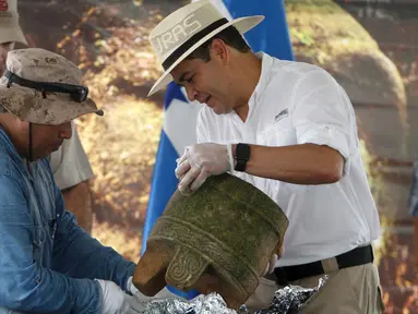 Presiden Honduras, Juan Orlando Hernandez (kanan) dan seorang arkeolog saat memamerkan benda kuno pada upacara di Catacamas, Honduras, (12/1). Benda - benda kuno ditemukan pada 2012 yang menyudut pada legenda "Kota Putih". (REUTERS / Jorge Cabrera