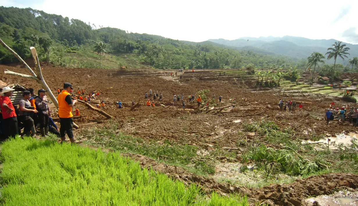 Tim SAR dibantu warga melanjutkan pencarian korban longsor di Desa Pasir Panjang, Salem, Brebes, Jumat (23/2). Proses evakuasi berjalan sulit, karena Tim SAR harus melewati endapan lumpur setinggi satu meter dan aliran air yang deras. (AFP PHOTO)