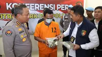 Mantan sekuriti yang menjadi kurir sabu memegang barang bukti di Polda Riau. (Liputan6.com/M Syukur)