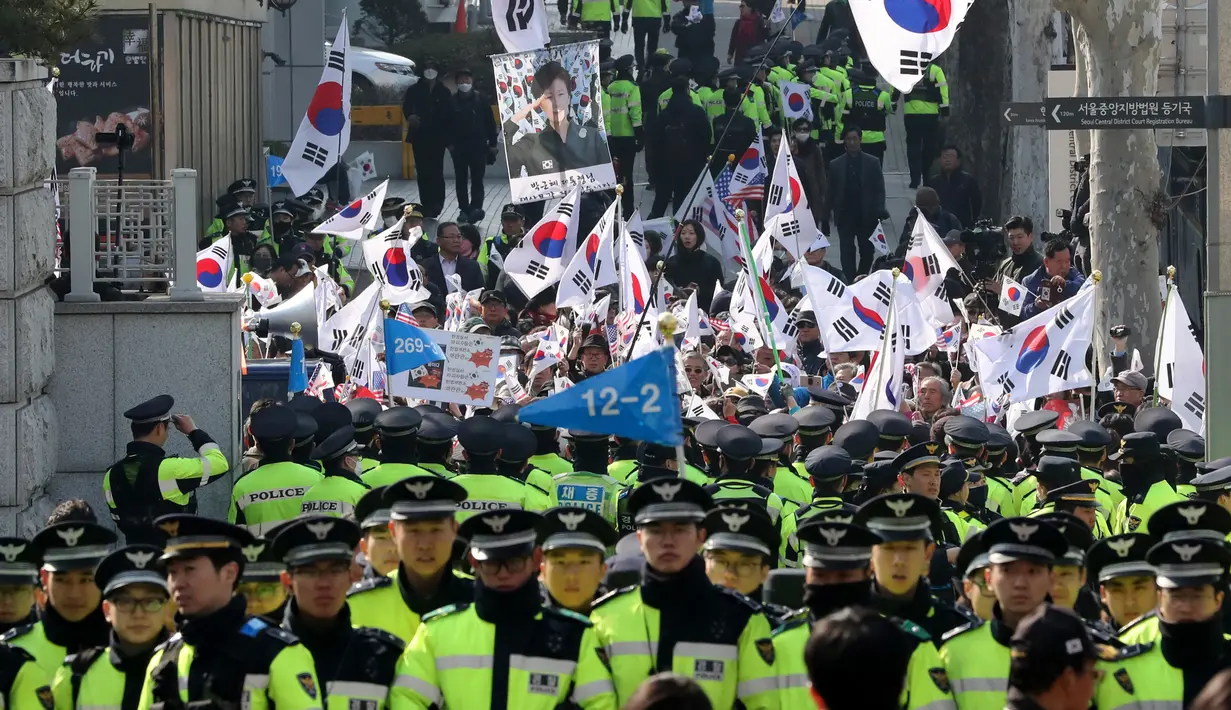 Pendukung mengibarkan bendera nasional dan membawa poster mantan Presiden Korsel, Park Geun-hye di luar kantor kejaksaan di Seoul, Selasa (21/3). Park memenuhi panggilan jaksa untuk diperiksa terkait skandal korupsi yang menyeretnya (AP Photo/Lee Jin-man)