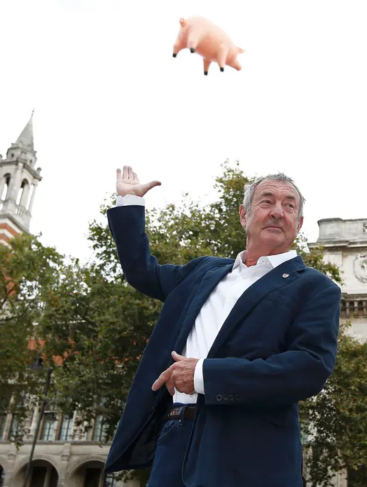 Drummer Pink Floyd, Nick Mason berpose dengan latar belakang balon udara berbentuk babi yang melayang di atas Victoria and Albert Museum untuk mempromosikan "The Pink Floyd Exhibition: Their Mortal Remains" di London, Rabu (31/8). (REUTERS/Peter Nicholls)