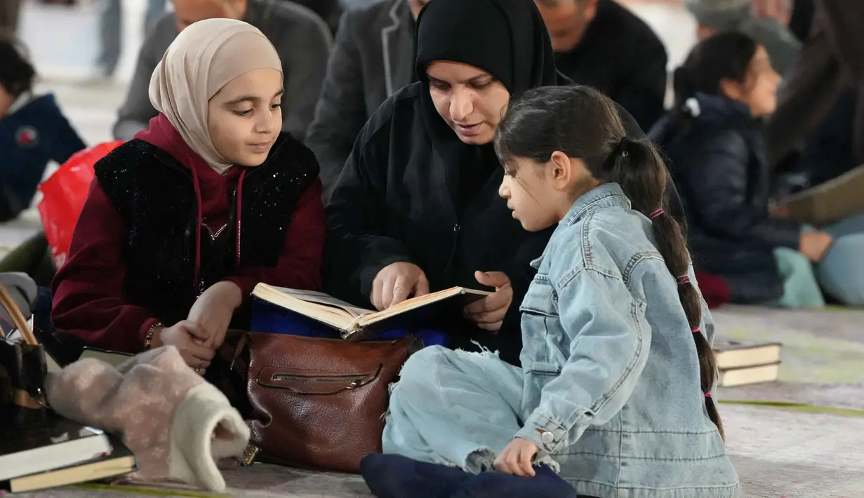 Diketahui, membaca Al Quran menjadi salah satu amalan utama untuk mendapatkan kemuliaan malam yang lebih baik dari seribu bulan tersebut. Tampak dalam foto, seorang wanita Muslim Syiah dan putrinya membaca Al-Quran, membaca Al-Quran, saat melaksanakan Itikaf di Masjid Kufa, selatan Baghdad, Irak, pada 12 Maret 2026. (Qassem al-KAABI/AFP)