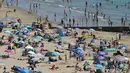 Para pengunjung berjemur menikmati sinar matahari di Pantai Bournemouth, Selatan Inggris pada Selasa 26 Mei 2026, saat kondisi gelombang panas menyebar ke sebagian wilayah tenggara Inggris dan London. (JUSTIN TALLIS/AFP)