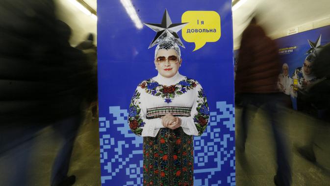 Sejumlah penumpang melewati poster yang menggambarkan penyanyi Ukraina Verka Serduchka dengan teks yang menyatakan 