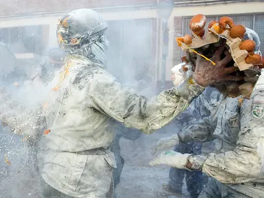 Orang-orang yang mengenakan pakaian militer ikut serta dalam perang makanan "Els Enfarinats" di Kota Ibi, Spanyol, 28 Desember 2022. Dalam festival musim dingin ini para peserta mengenakan pakaian militer dan mementaskan tiruan kudeta di luar balai kota. (JAIME REINA/AFP)